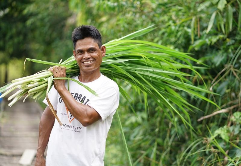 Lokale werknemer houdt planten vast en lacht naar de camera